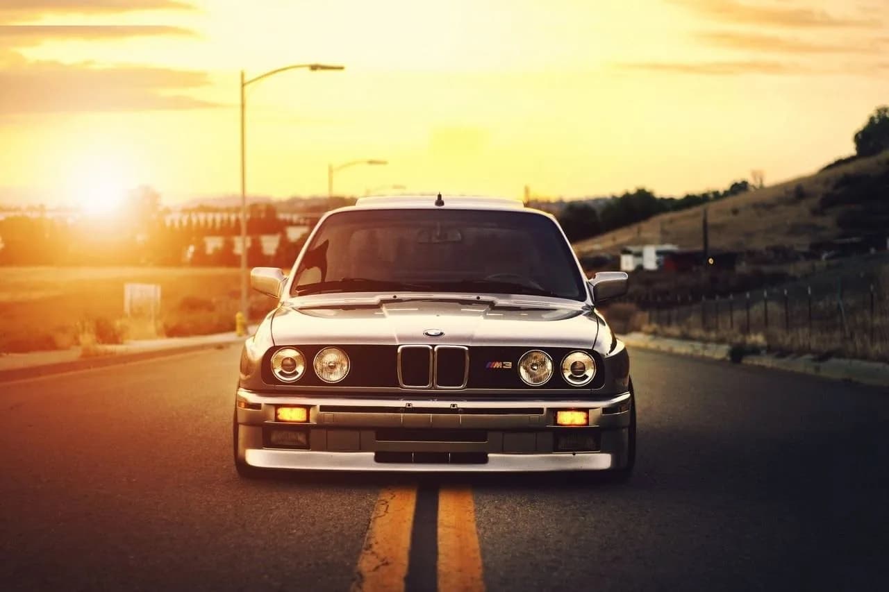 Front view of a BMW E30 M3 at sunset